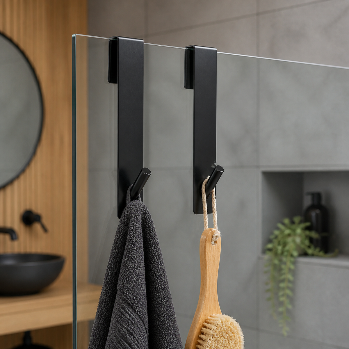 Deux crochets longs noirs Brumeo sur paroi de douche avec serviette et brosse